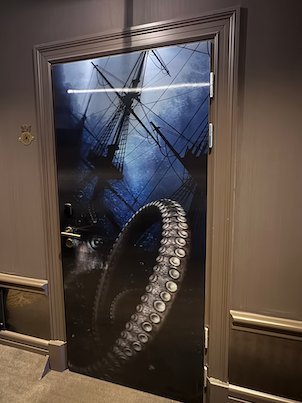 Hotel room door with a picture of a sailing ship and a large tentacle