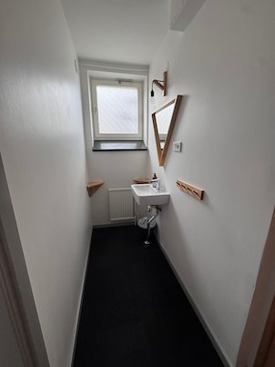 Narrow white hotel bathroom with a small sink, a mirror and a window