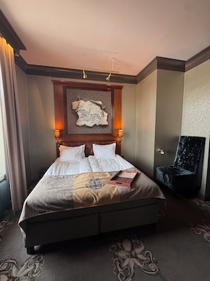 Hotel room with a double bed, a carpet with octopus patterns and a black velvet chair