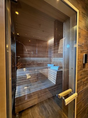 Small wooden sauna behind a glass door in a hotel room