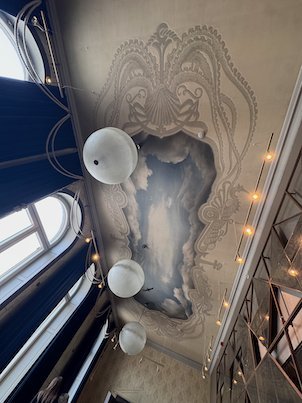Ceiling painted with a sea monster and round lamps in a hotel corridor in Umeå