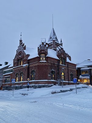 Ornate red brick building with towers and gables in snowy central Umeå