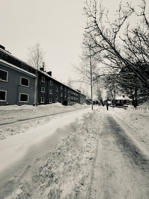 Snowy street with apartment blocks and bare trees in Umeå