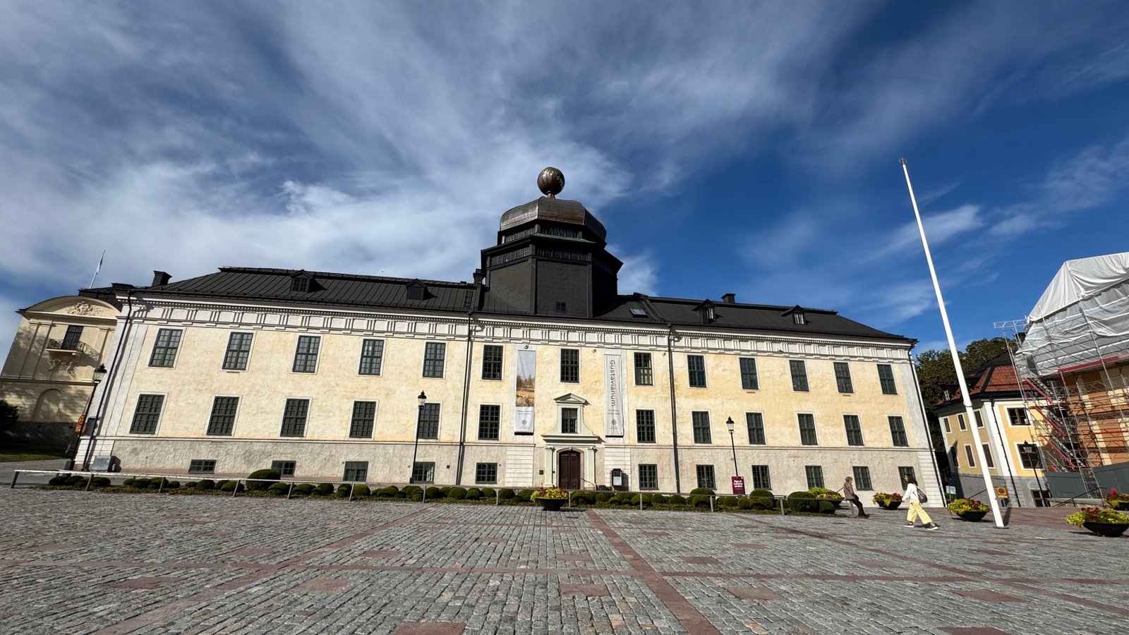 Gustavianum museum in Uppsala, a yellow building with a dark dome, under a blue sky