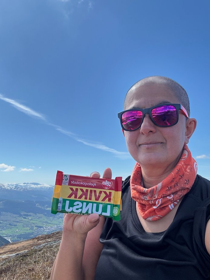 Selfie with pink sunglasses holding a Kvikk Lunsj chocolate bar on the mountain