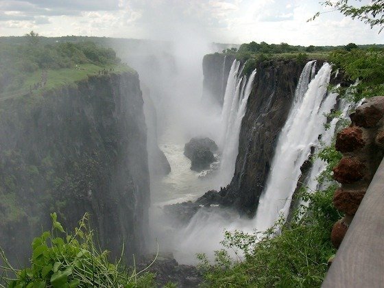 Water falls into a deep gorge and spray rises at Victoria Falls in Zimbabwe.