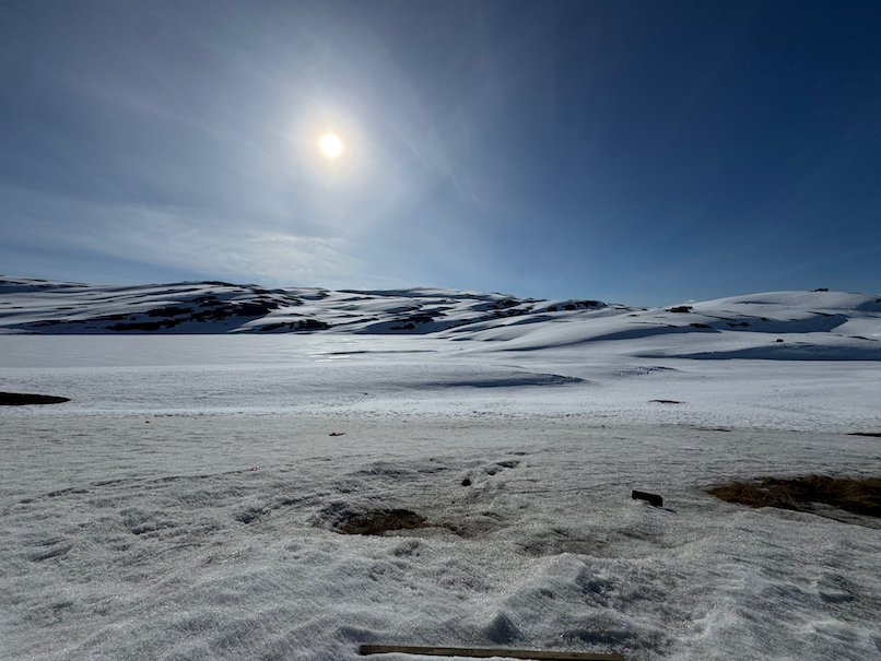 Snowy mountain plateau on Vikafjellet with the sun behind thin clouds