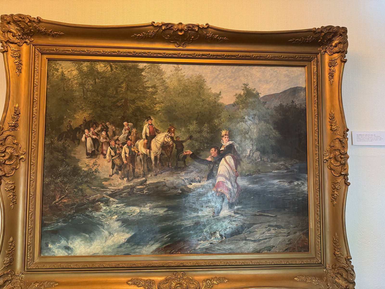 Old painting of people by a river in a gold frame at Voss Folkemuseum