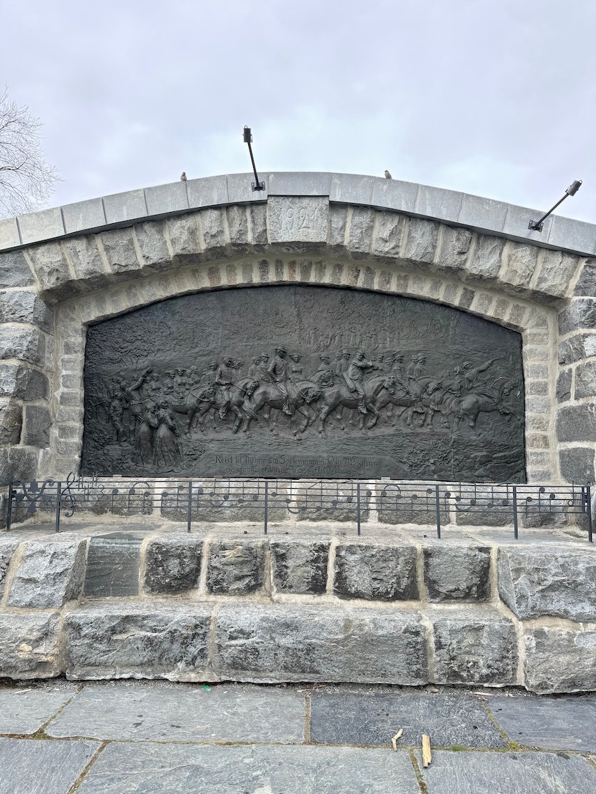 Memorial wall with a stone relief of people in Voss