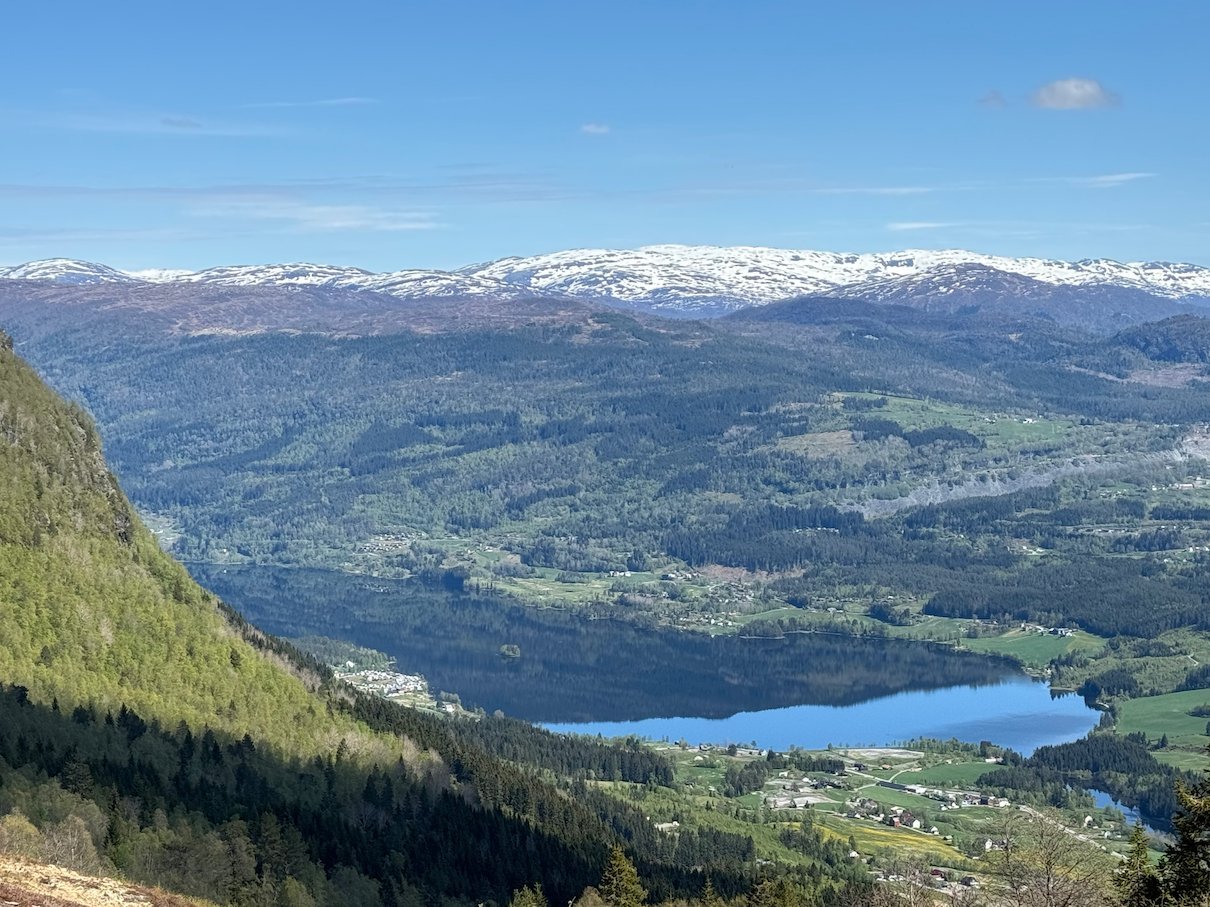 View down to the Voss valley and lake Vangsvatnet from the mountain, with snowy peaks