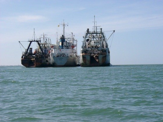 Three large fishing trawlers lie at anchor in the calm sea off Walvis Bay in Namibia.