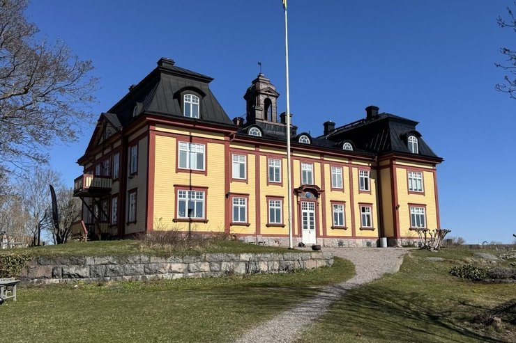A yellow manor house with a gravel path near Stockholm, photographed by Zayera Khan