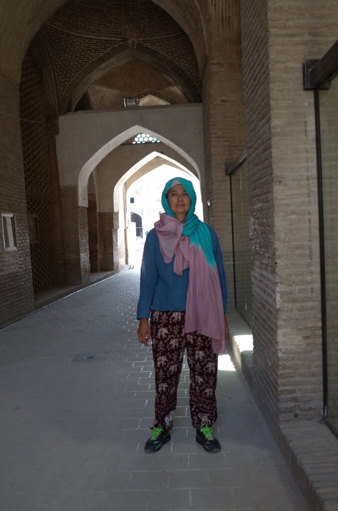 Zayera Khan in a turquoise scarf in a passage of the Jameh Mosque of Isfahan