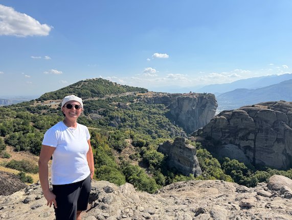 Zayera Khan in a white shirt on a rocky viewpoint at Meteora