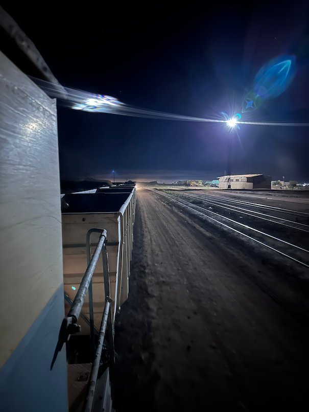 Ore wagons stand under bright lights at the Zouerat station at night.