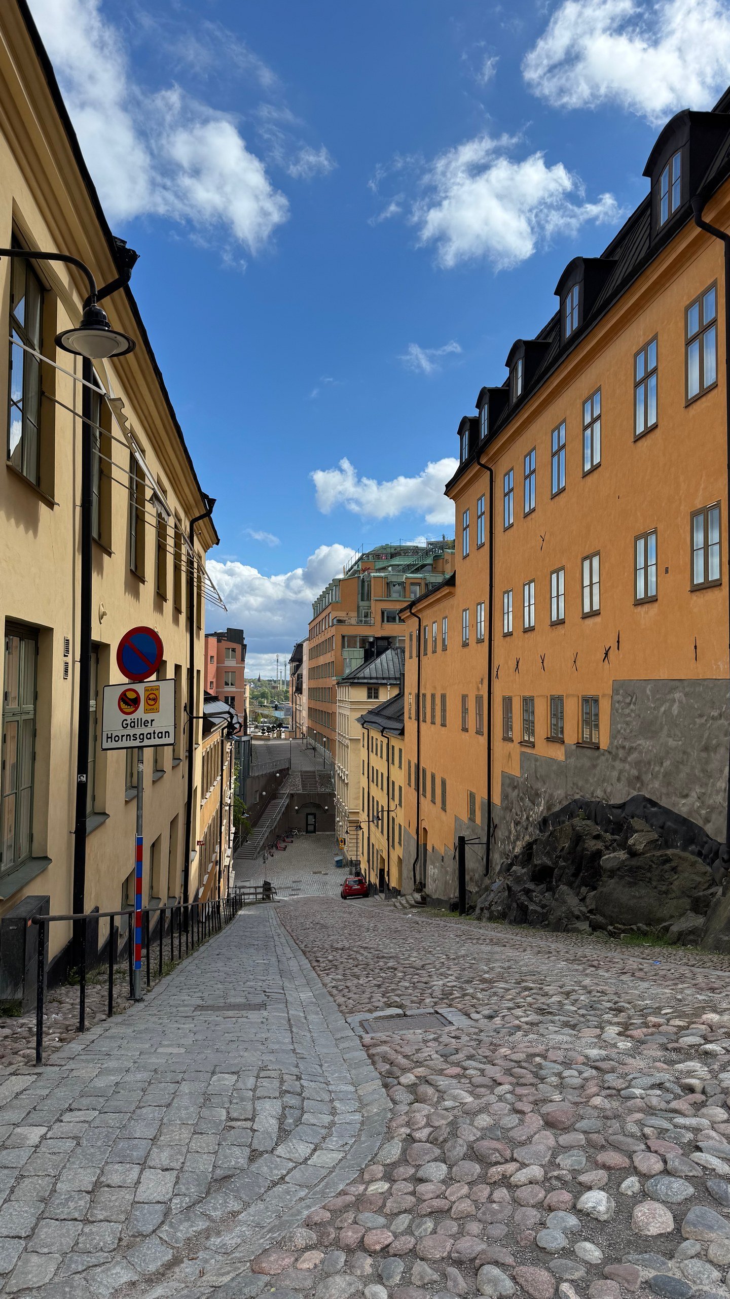 A cobblestone street with yellow houses on S&ouml;dermalm, Stockholm, photographed by Zayera Khan