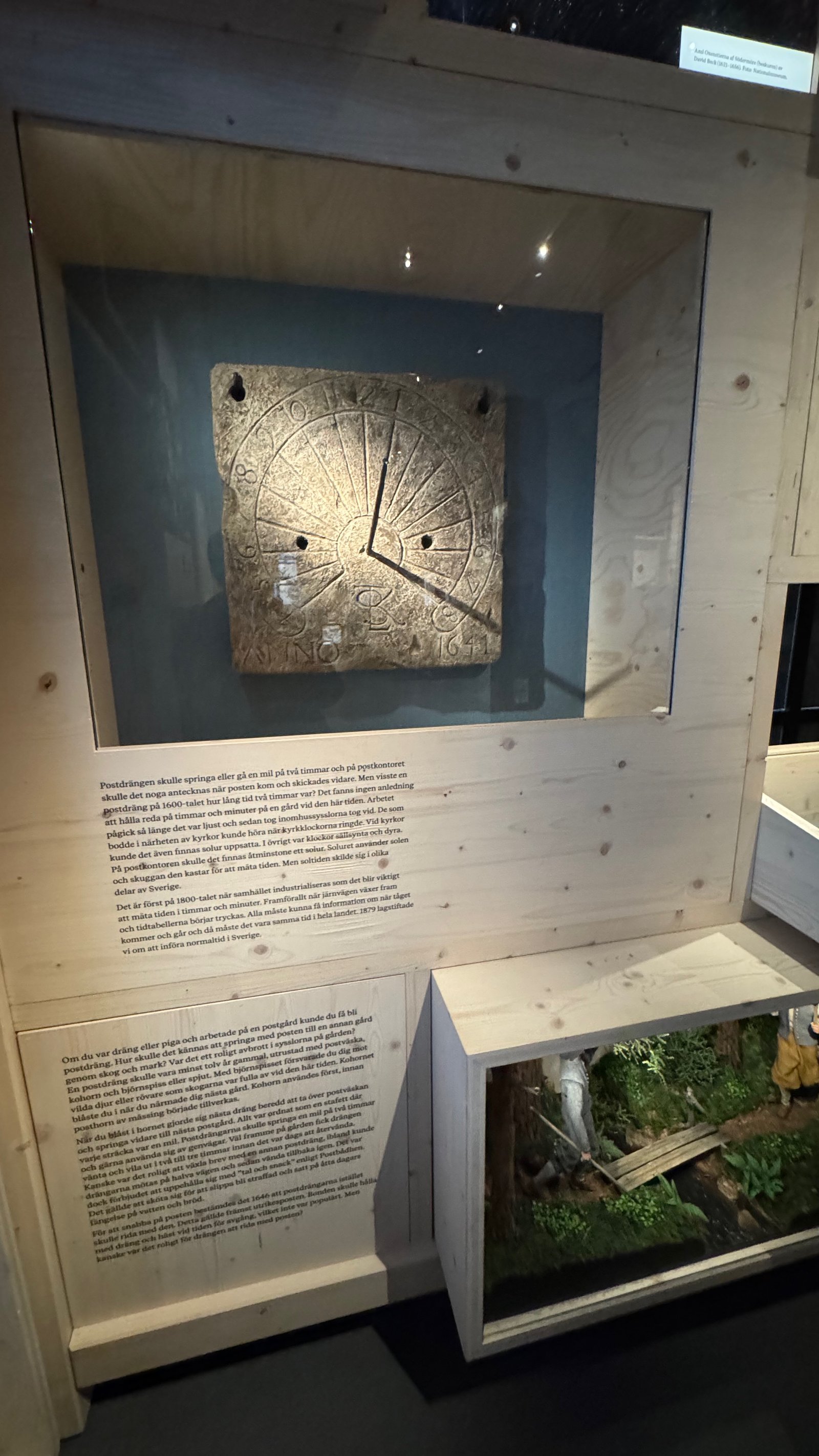 A carved stone sundial dated 1641, displayed in a glass case, once used to measure time at a postal station.