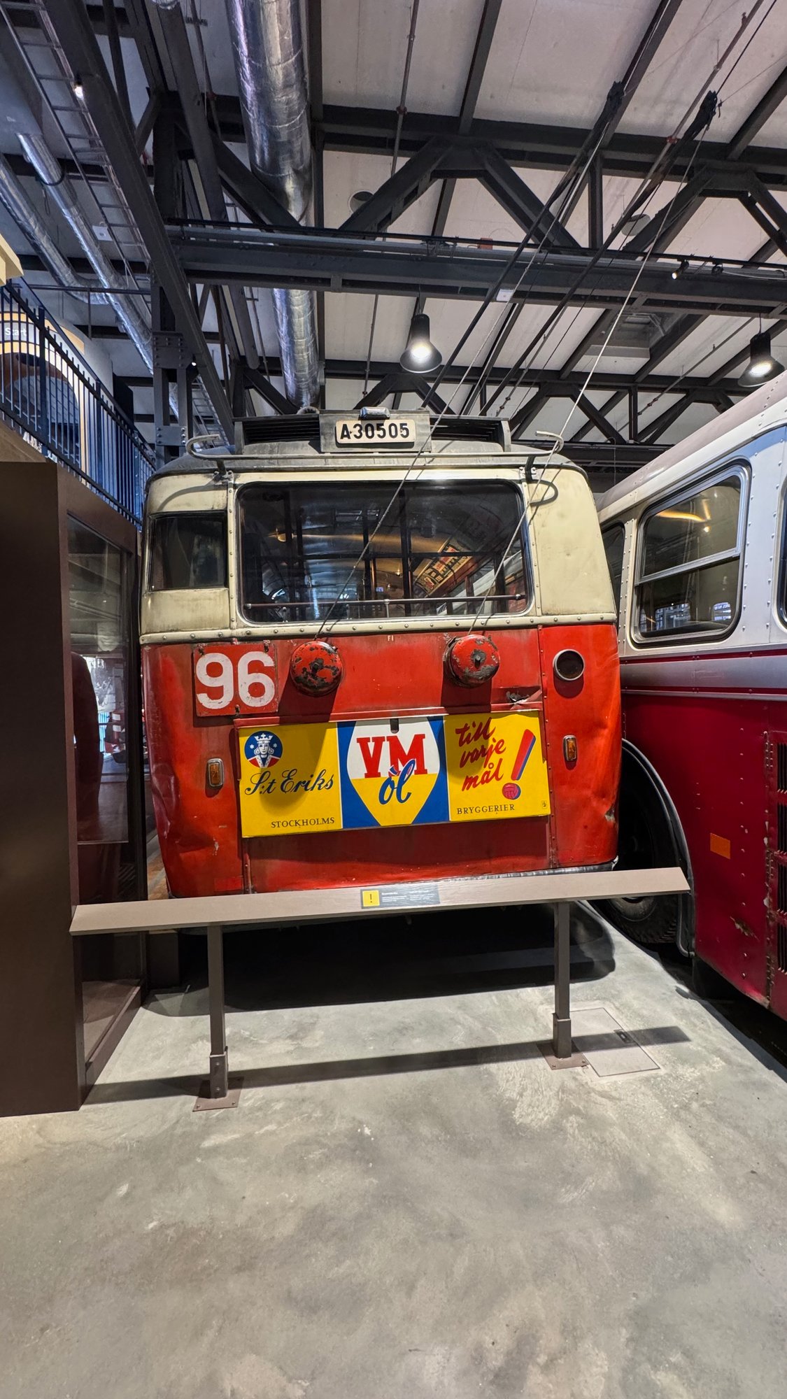 Rear of a red and cream trolleybus with the number 96, the plate A 30505, two trolley poles on the roof and a yellow advertisement for St Eriks VM öl.