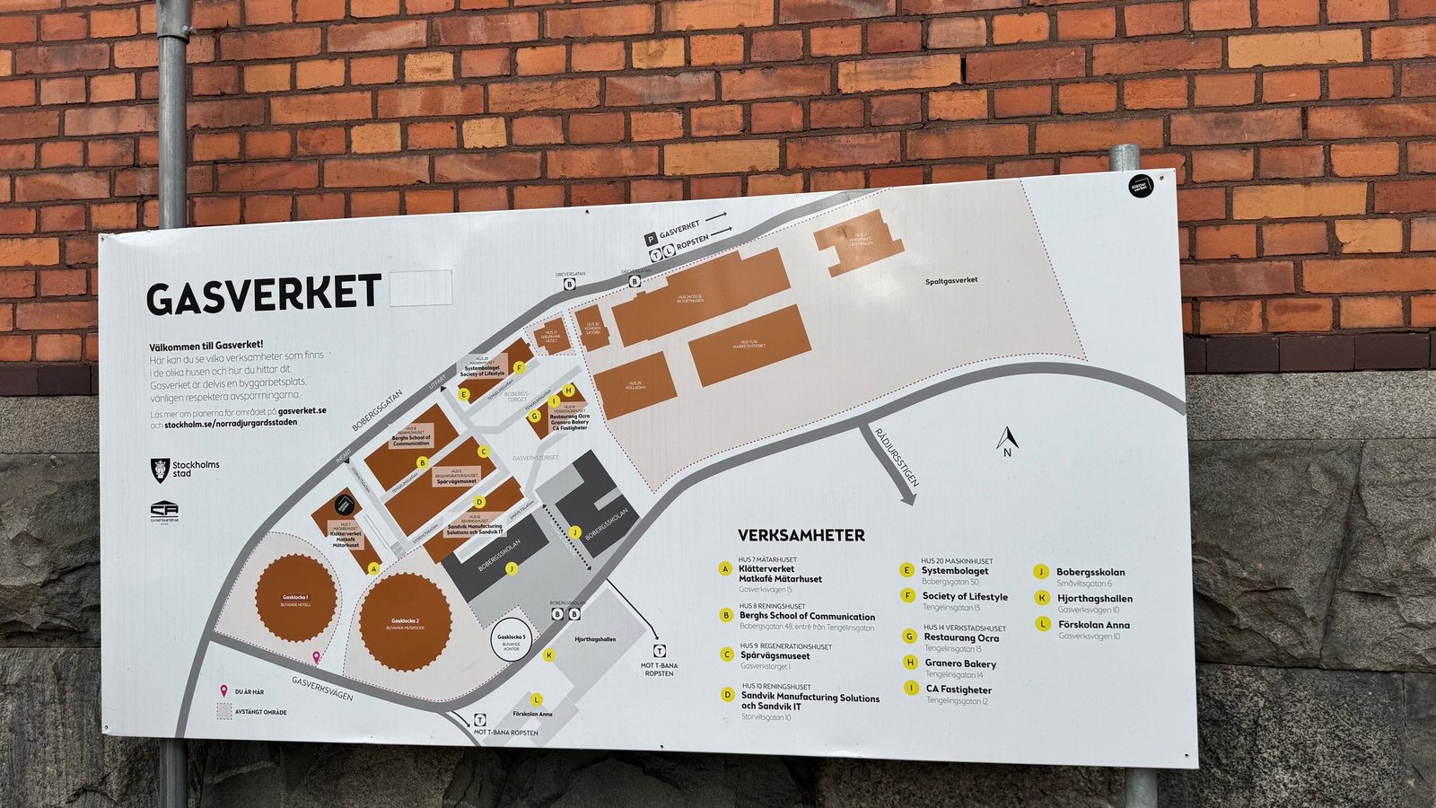 Outdoor map sign titled Gasverket on a brick wall. A list of businesses names Spårvägsmuseet in Hus 9, Regenerationshuset, at Gasverkstorget 1.
