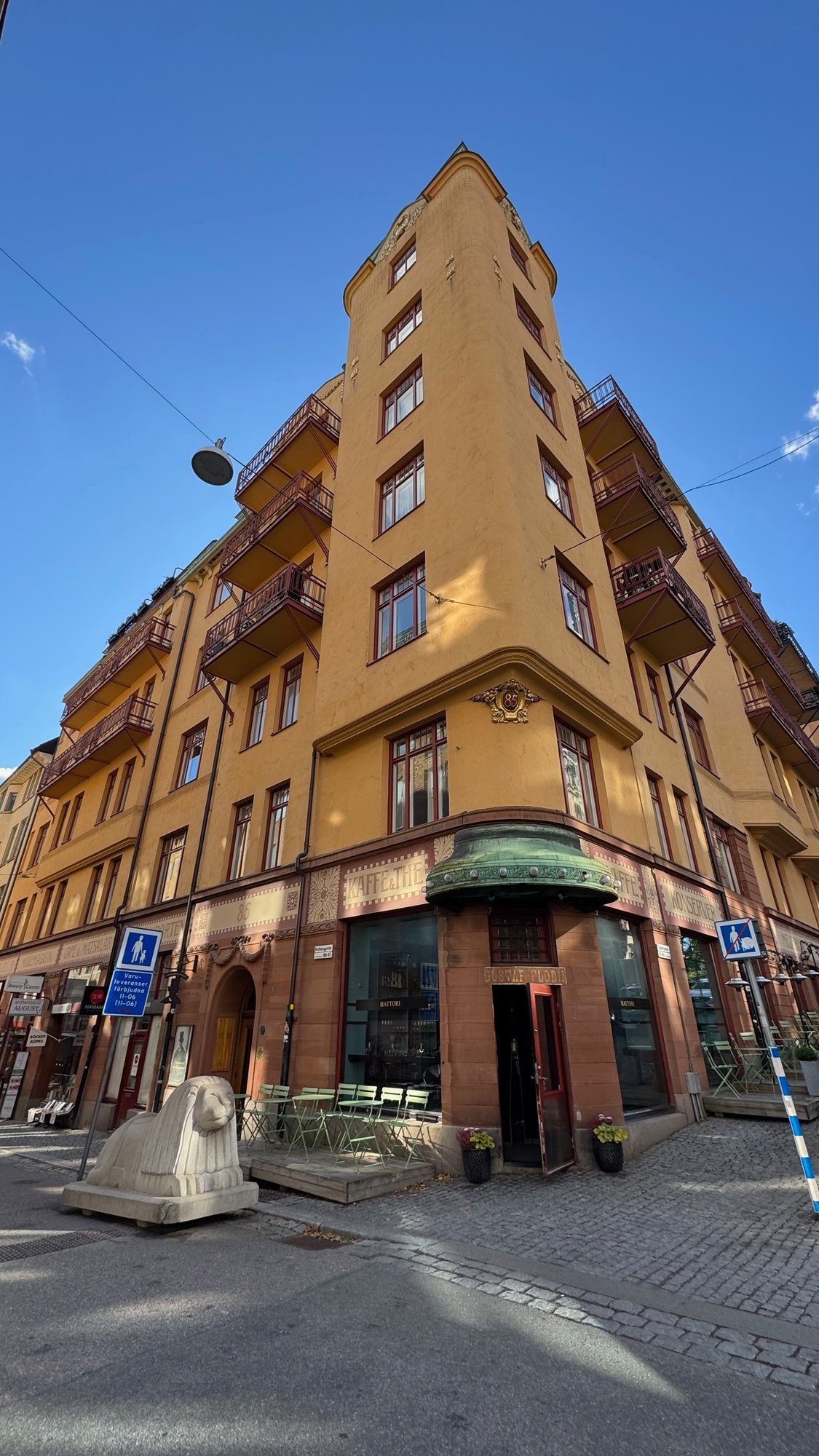 Yellow-orange apartment building on a street corner, seen from below under a blue sky.