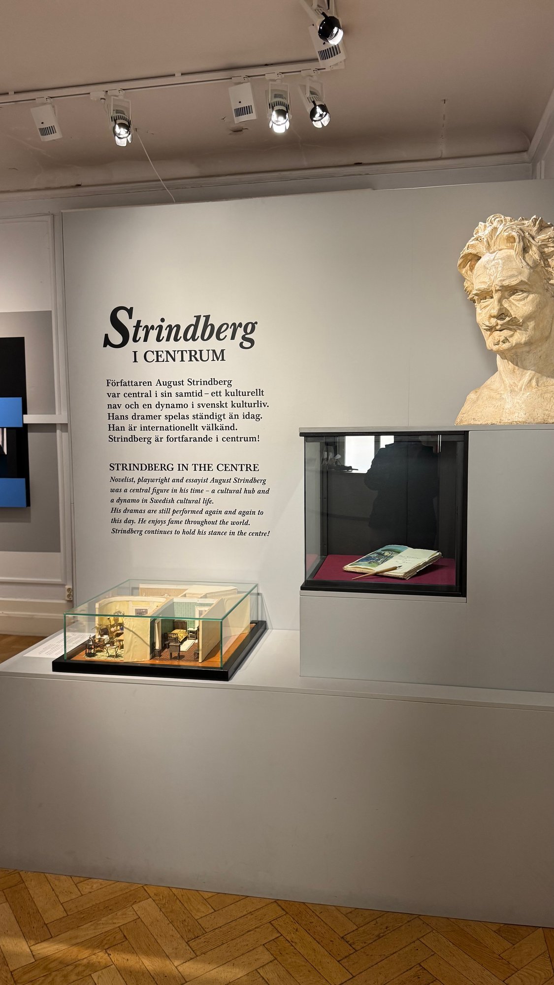 Exhibition wall with the title Strindberg i centrum, a plaster bust and display cases.
