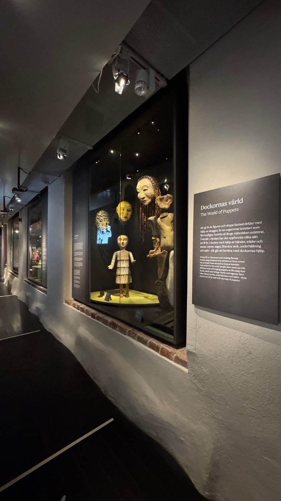A lit showcase with puppets and masks in the exhibition The World of Puppets at Scenkonstmuseet.