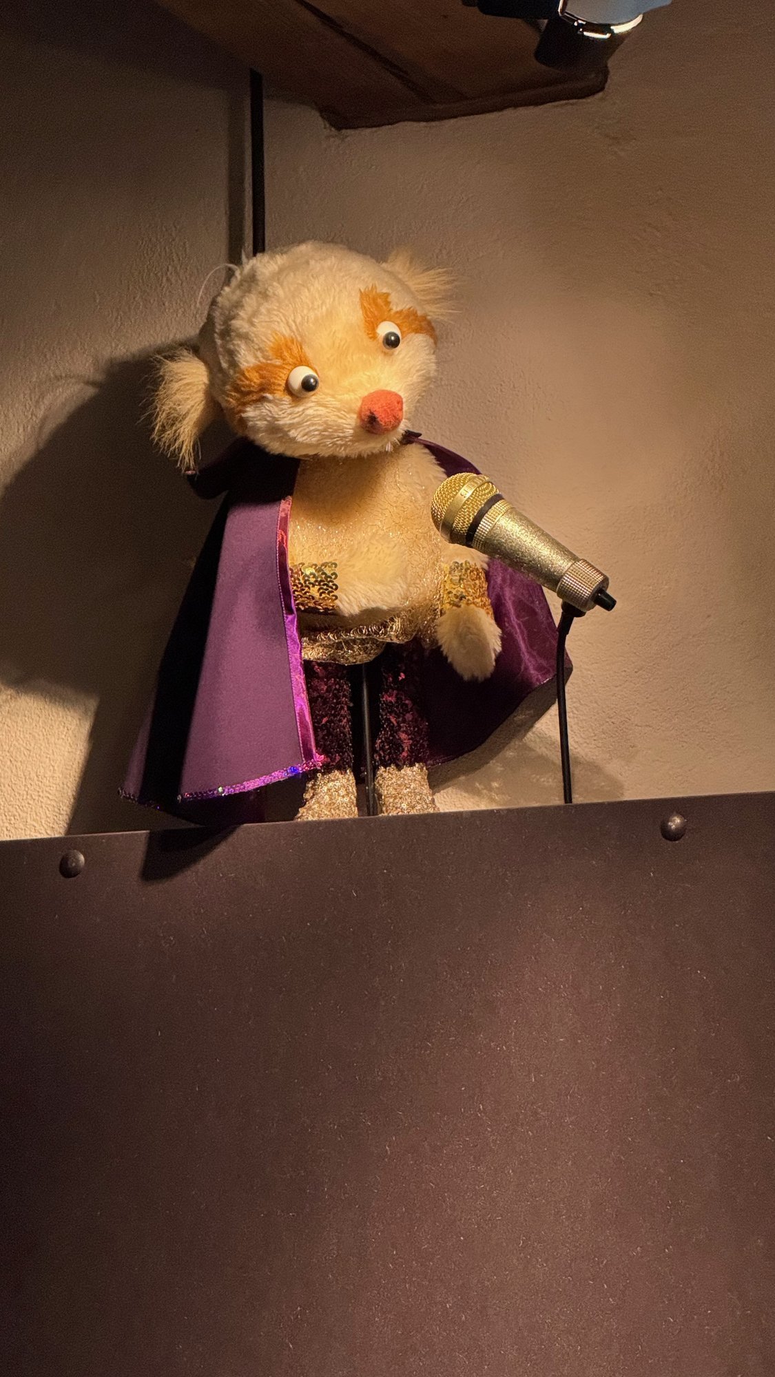 A furry puppet in a purple cape holds a microphone at Scenkonstmuseet.