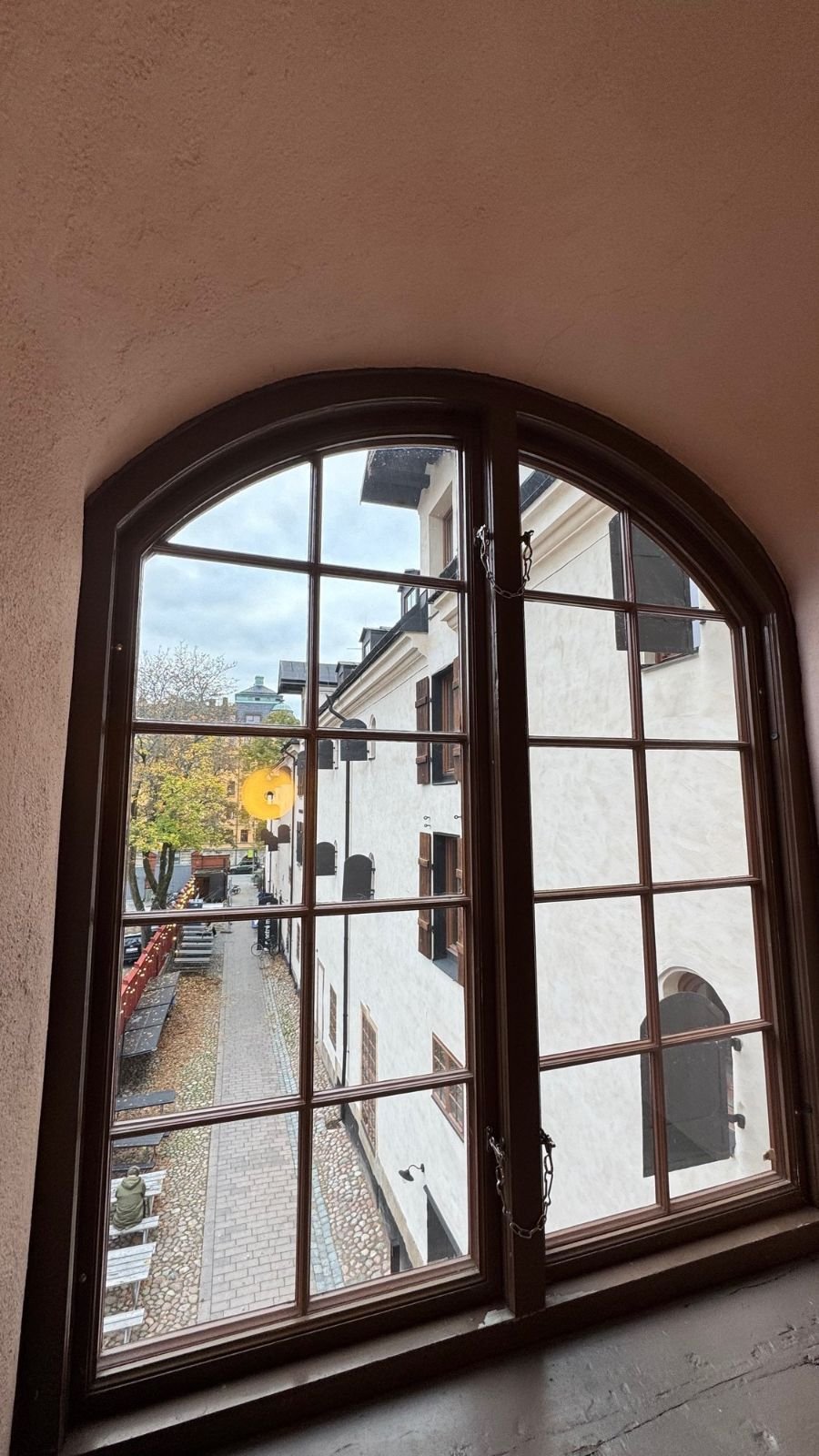 An arched window looks down on the lane and old buildings next to Scenkonstmuseet.