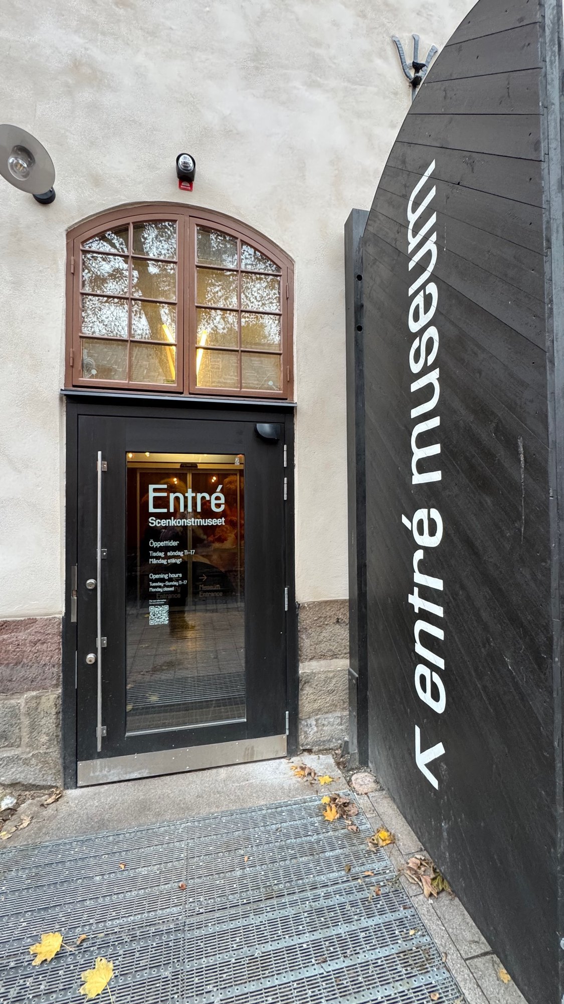 The glass entrance door of Scenkonstmuseet with an arched window and a black entré museum sign.