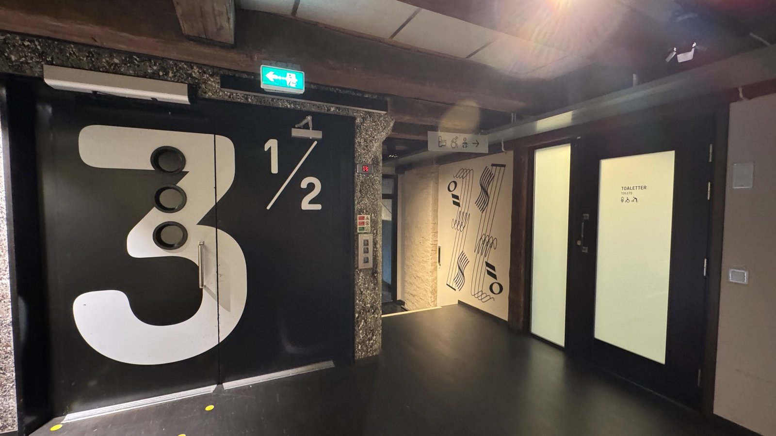 A black door with a large number 3 ½ marks a floor level, with white doors to the right, at Scenkonstmuseet.