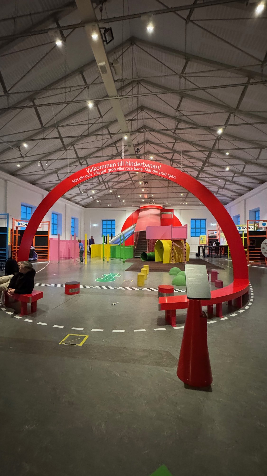 A large hall with an obstacle course for children, a red arch and colorful blocks at Tekniska museet.