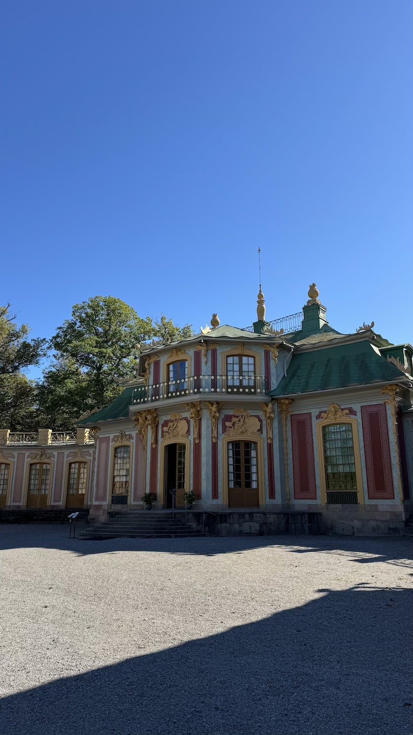 The pink and yellow rococo facade of the Chinese Pavilion at Drottningholm, with its domed towers against a clear sky.
