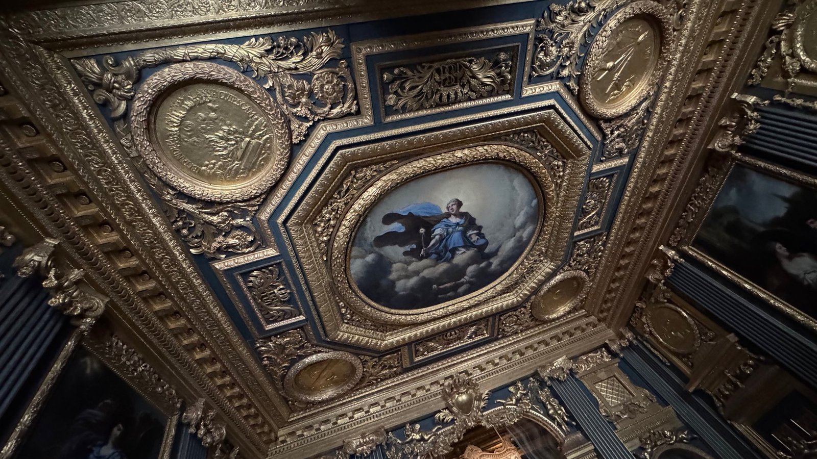 Coffered ceiling in Hedvig Eleonora's State Bedchamber with gilded frames, medallions and a painted oval of a figure in a blue sky.