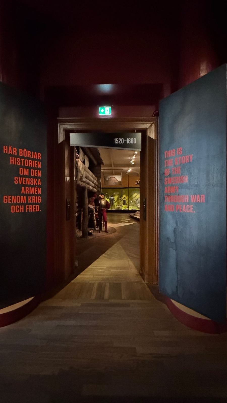 A dark corridor with red and blue walls leads into the permanent exhibition at Armémuseum.