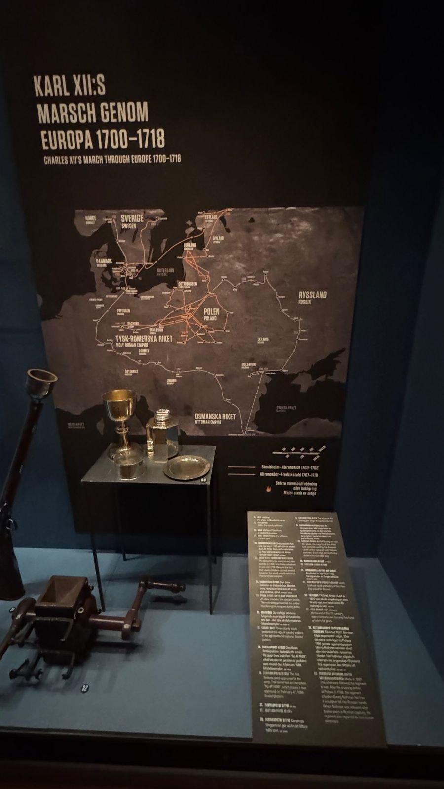 A map of the march of Karl XII through Europe from 1700 to 1718 above a showcase with a goblet, a plate and other objects at Armémuseum.