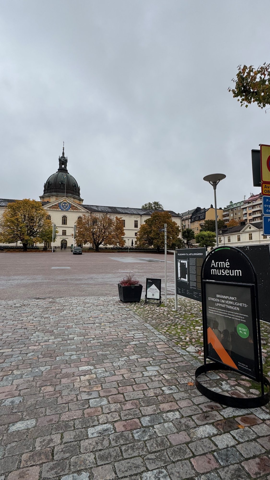 A cobblestone square with the Armémuseum sign and the domed main building in the background.