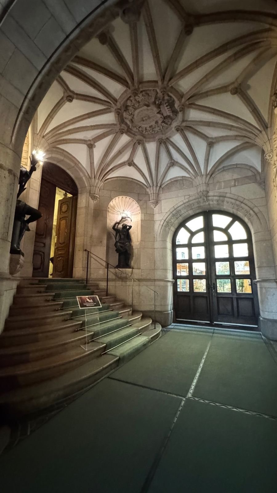 The stone entrance hall of the Hallwyl Museum with a ribbed vault, stairs and figures in wall niches.