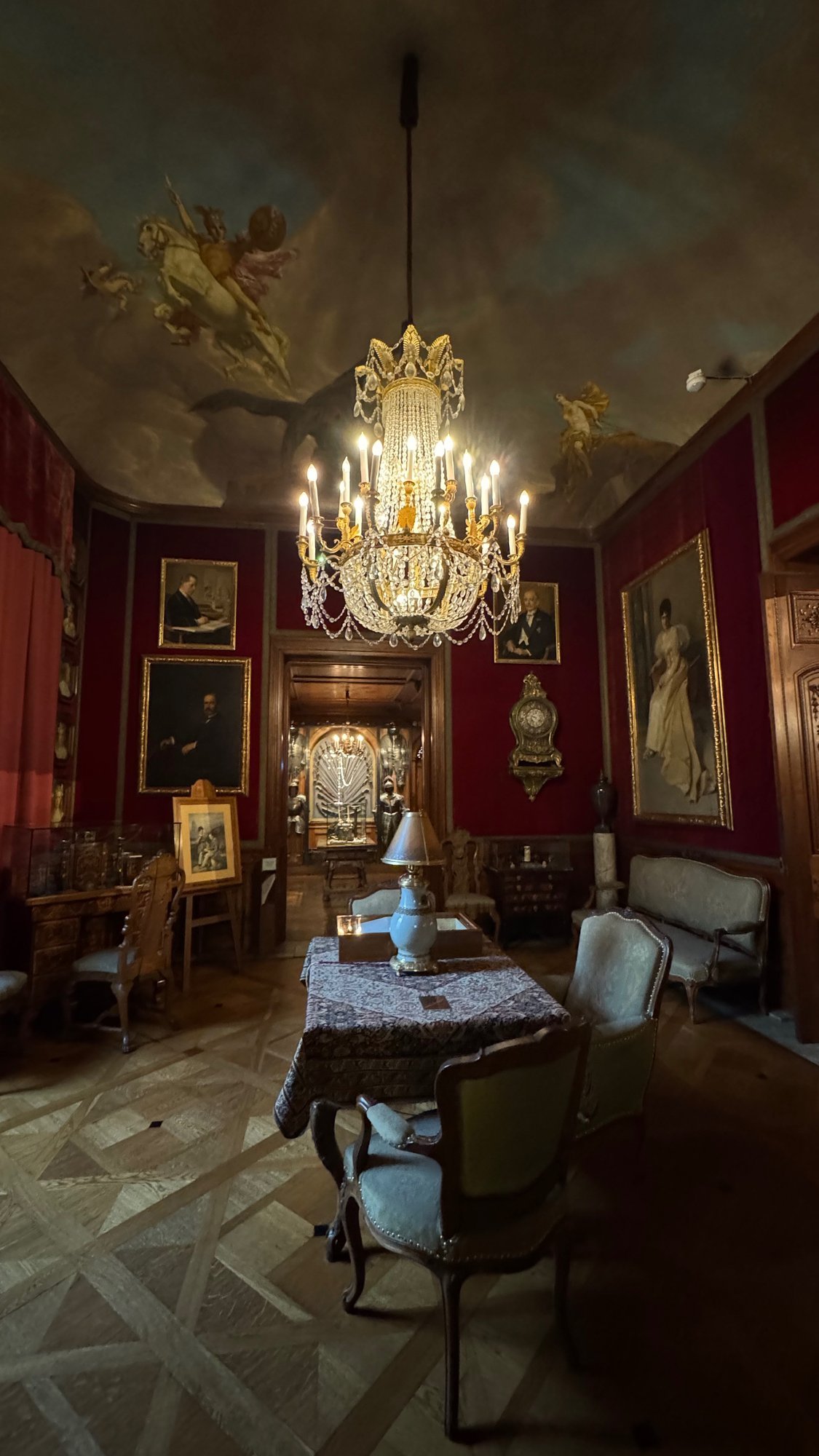 A red salon with a crystal chandelier, paintings and old furniture at the Hallwyl Museum.