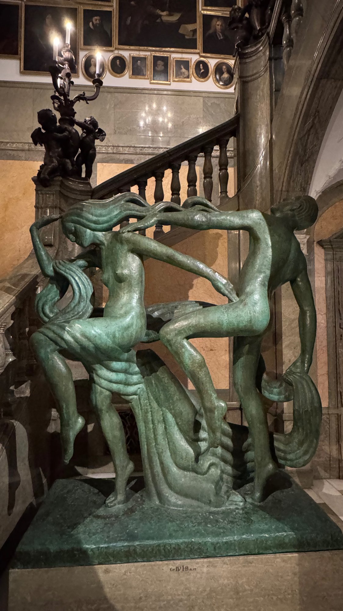 A green bronze sculpture of two dancing figures stands by the main staircase of the Hallwyl Museum.