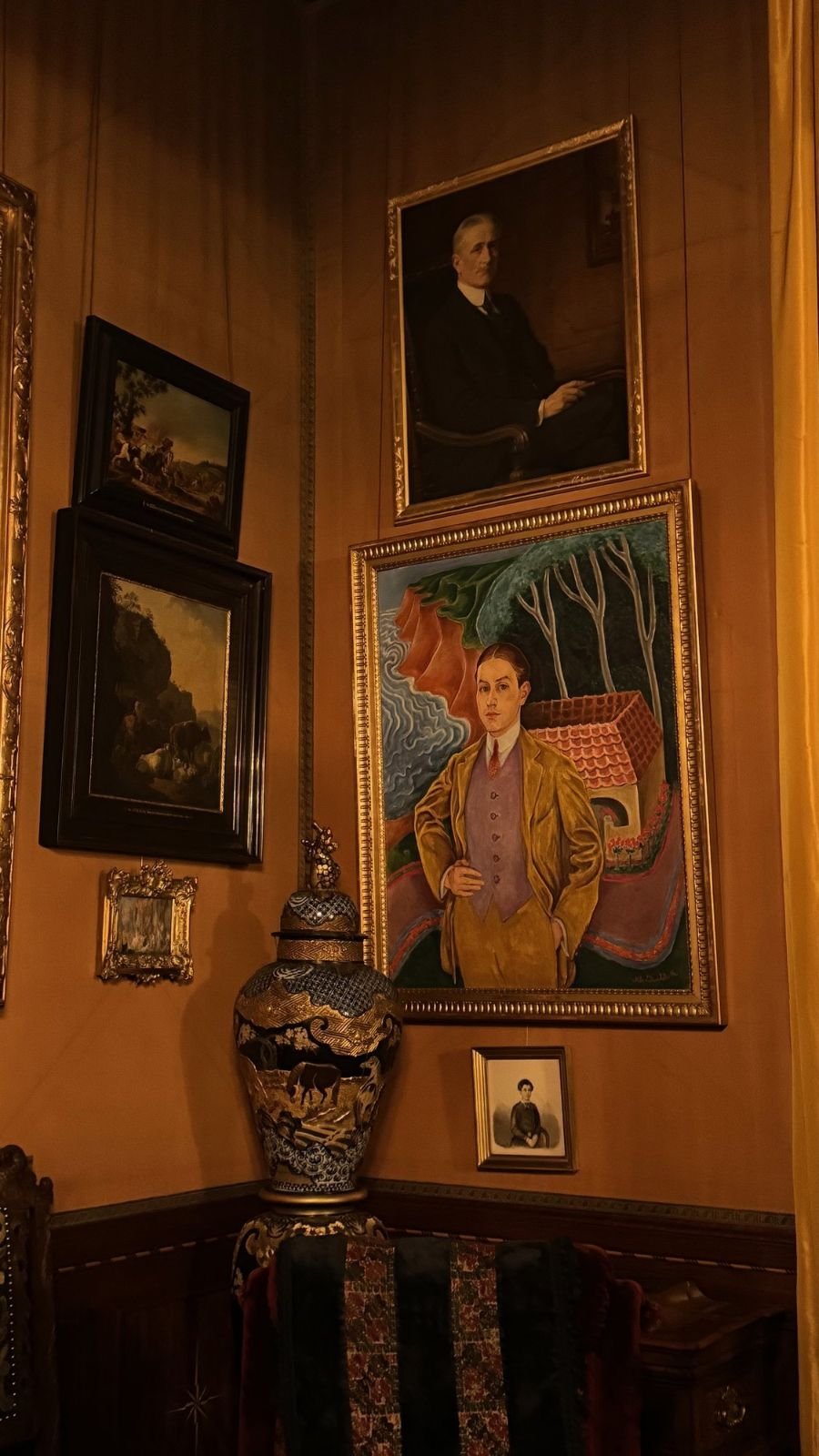 A portrait of Rolf de Maré by Nils Dardel in a gold frame next to a tall vase on a wooden cabinet at the Hallwyl Museum.