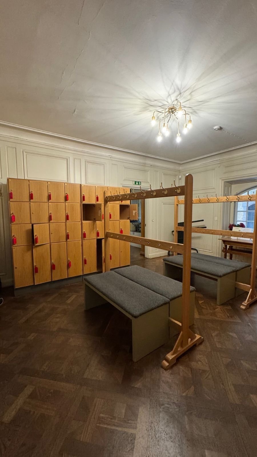 A cloakroom with wooden lockers, benches and coat racks at the Hallwyl Museum.