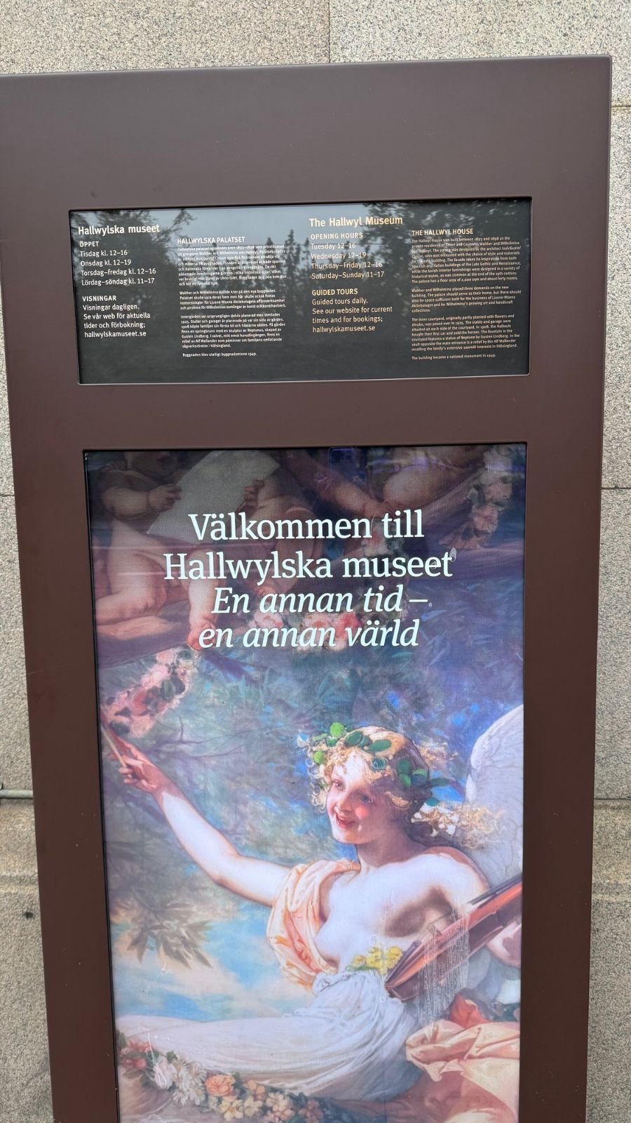 A sign with opening hours and a painted angel says Välkommen till Hallwylska museet at the entrance.