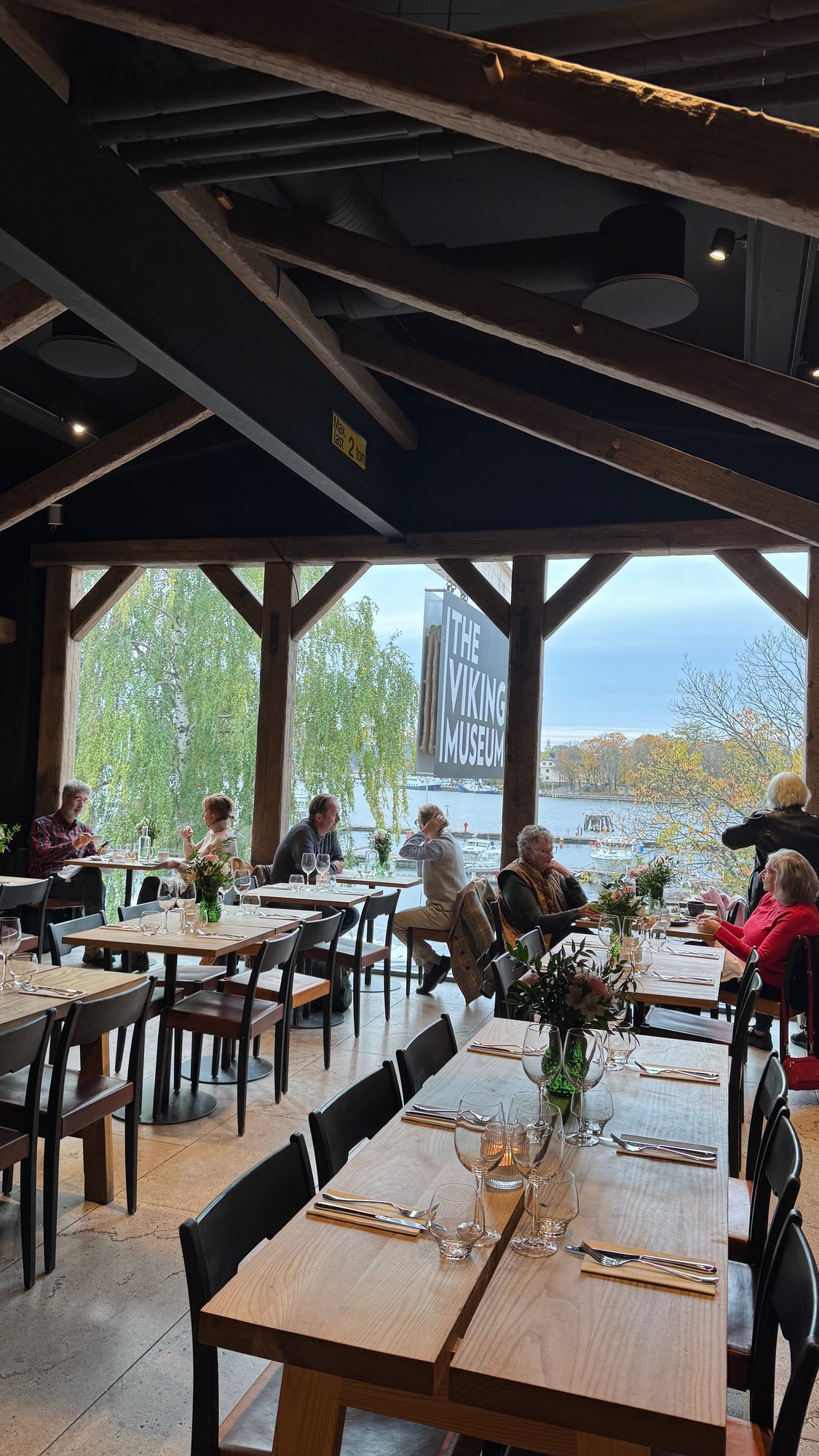 The restaurant at The Viking Museum with wooden tables, a beamed roof and large windows facing the water.