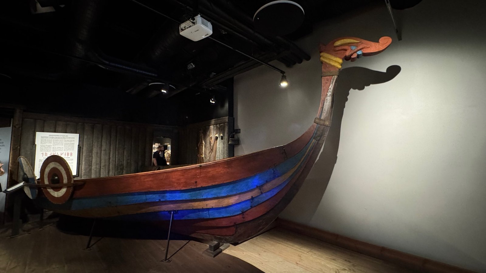 A wooden Viking ship painted in red, blue and yellow stripes, with a carved prow and round shields.