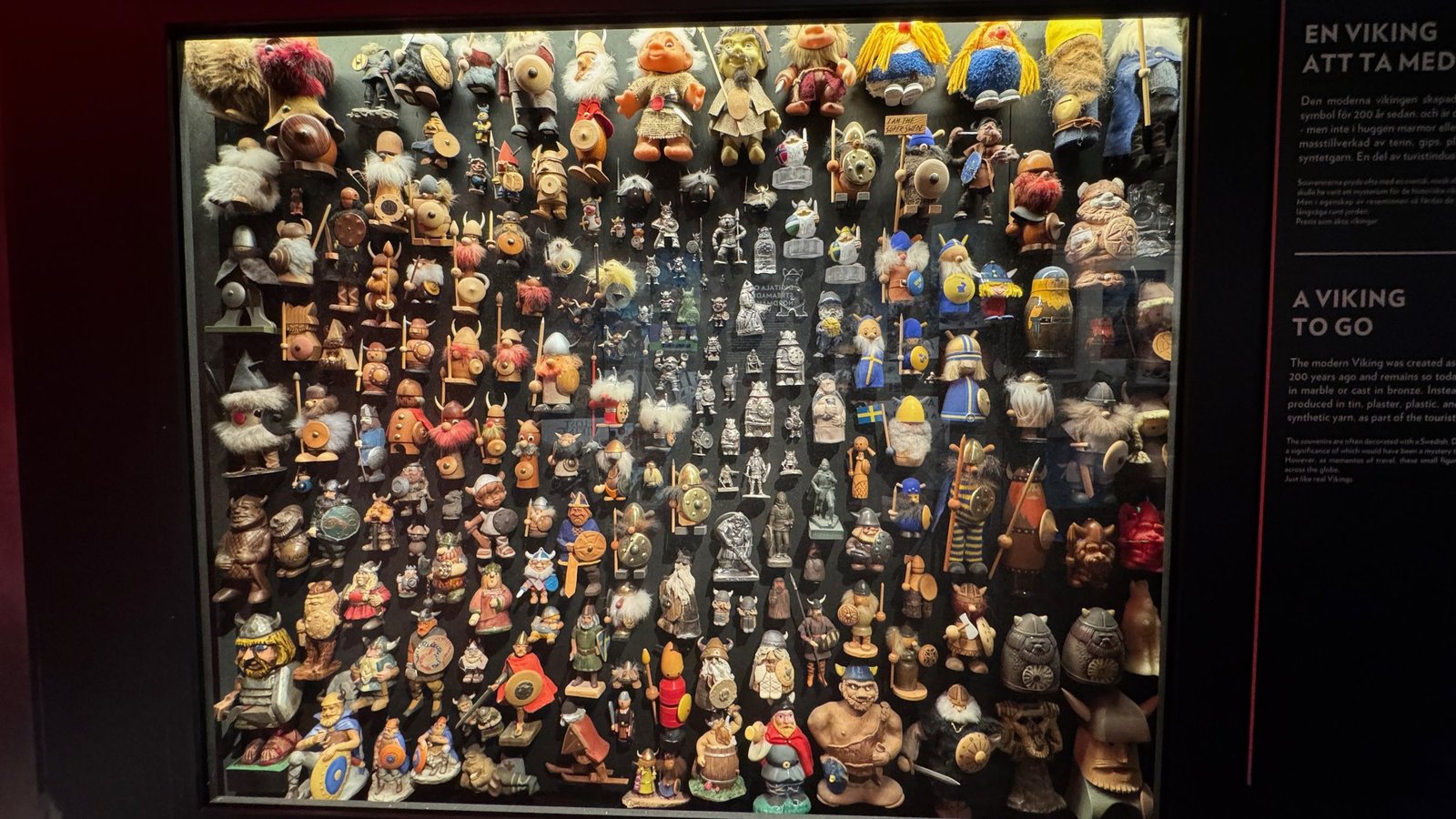 A large glass case filled with hundreds of souvenir Viking figurines, many with horned helmets.