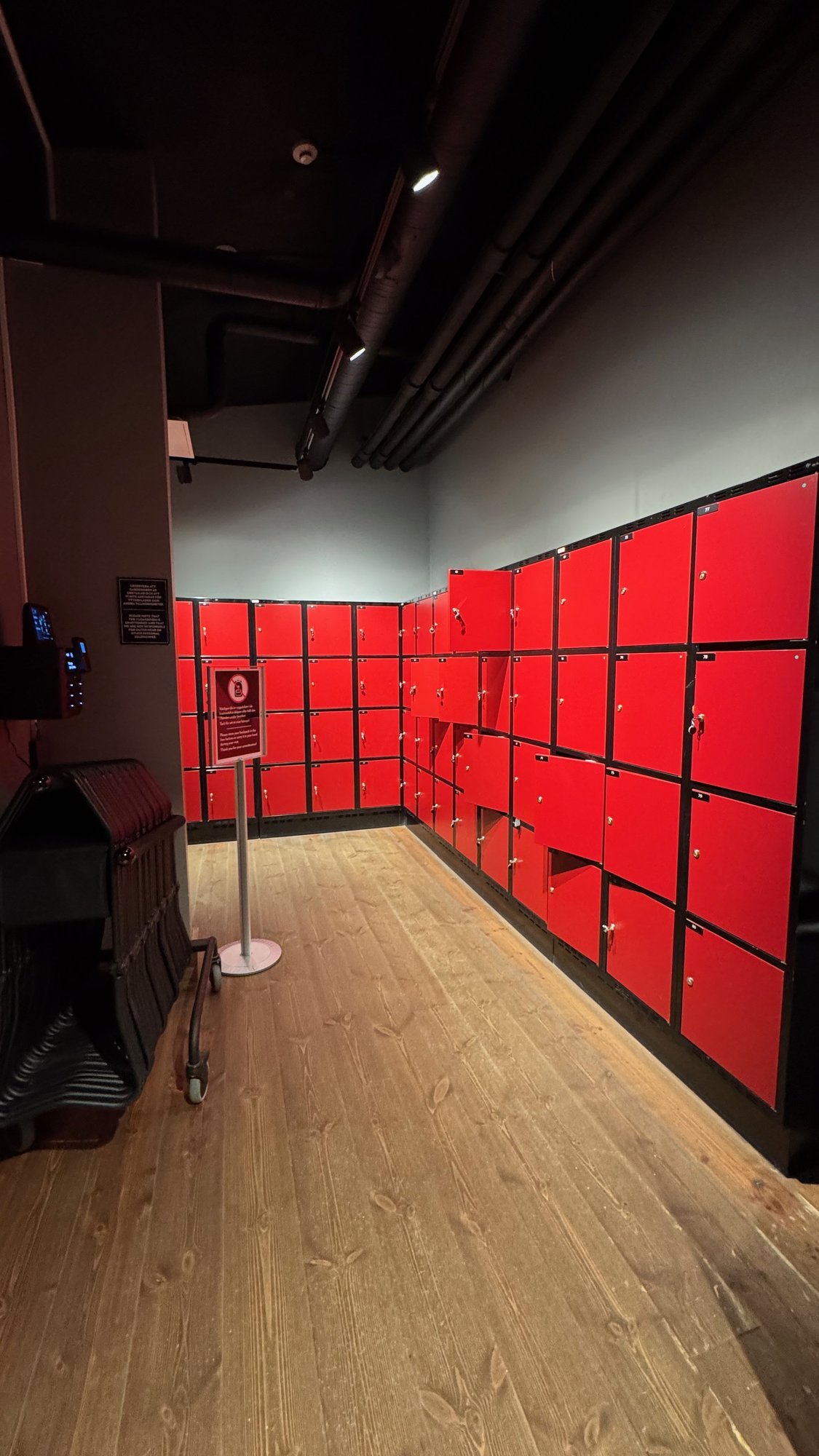 A row of red lockers along a wall, with a wooden floor.