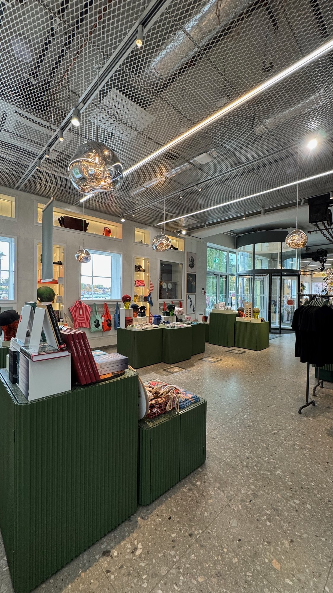The museum shop at Vrak Museum of Wrecks with green displays, glass lamps and a terrazzo floor.