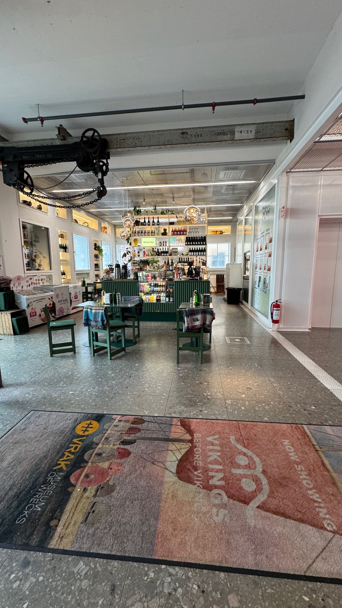 A long bright hall at Vrak Museum of Wrecks with the shop and caf&eacute;, and a large Vrak doormat at the door.
