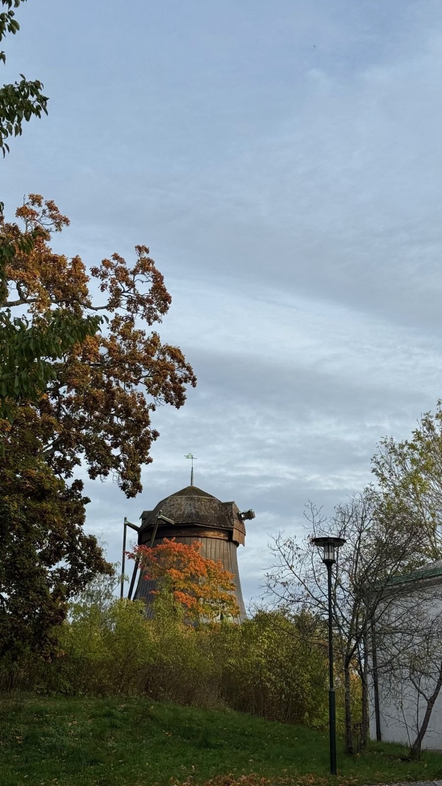The old wooden mill at Waldemarsudde with red and yellow autumn trees around it.