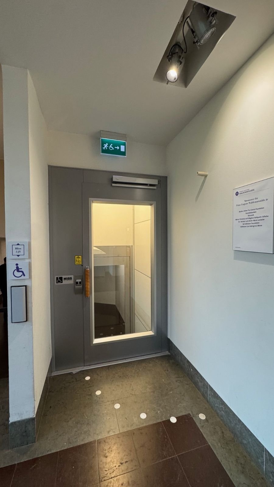 A lift door with a glass window and a wheelchair sign at Waldemarsudde.